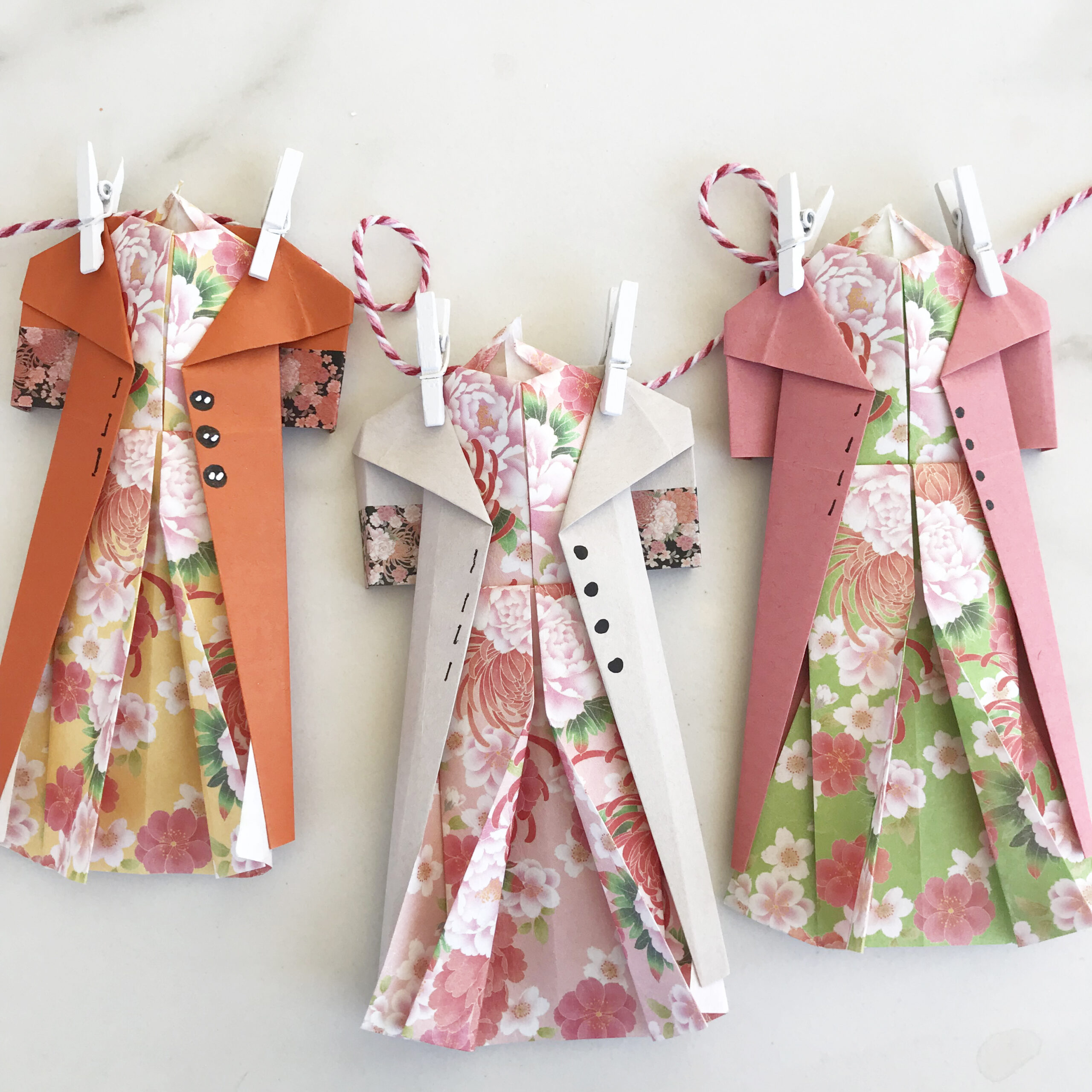 origami dresses and coats clipped with mini clothes pins to bakers twine