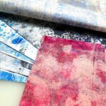 close up of a red gel printed washi paper sheet on top of a stack of blue gel printed washi paper sheets