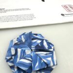 origami tato envelope folded out of washi paper with abstract blue lines printed on it and a washi paper pad in the background