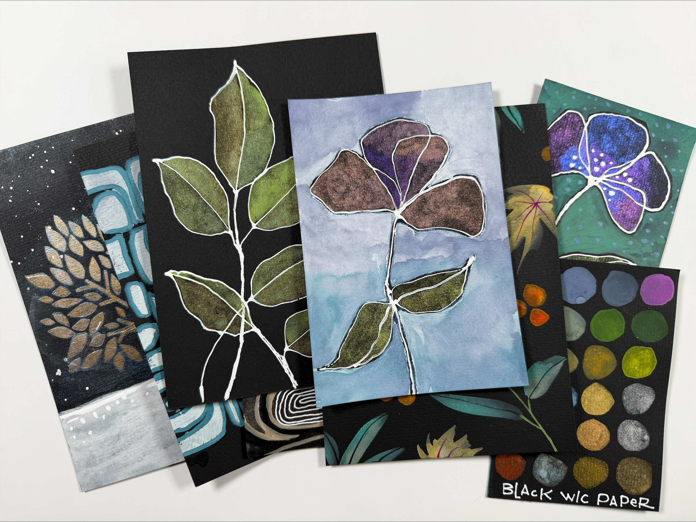 spread of leaf watercolor paintings on black paper