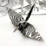 spread of suminagashi prints, or Japanese ink marbling, with an origami crane folded out of suminagashi paper in the foreground