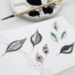 Watercolor and sumi ink leaves on Torinoko paper with a porcelain palette filled with ink and a sumi brush in the background