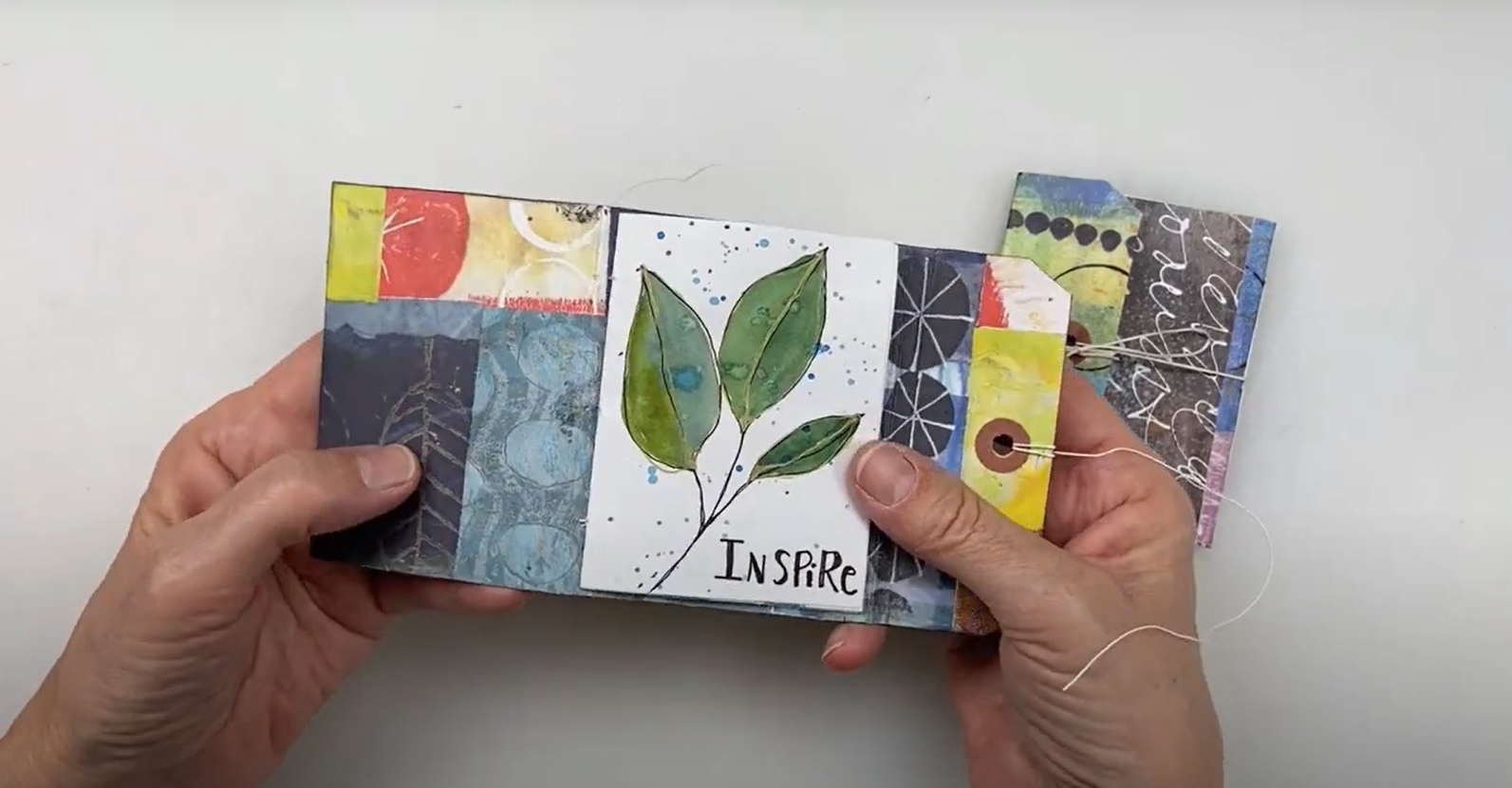 completed tag book with watercolor leaves and the word "inspire" written on the first page