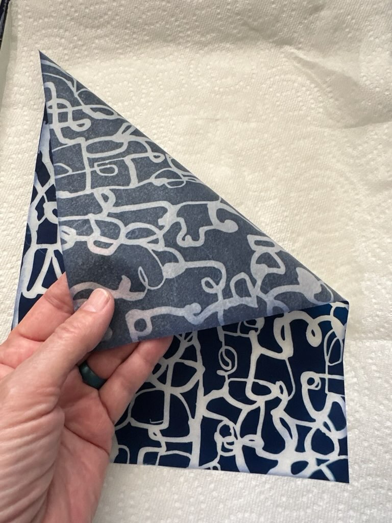 hand folding over the corner of a washi paper with abstract cyanotype print
