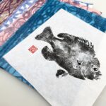 spread of colorful printed washi papers with a gyotaku fish print on top