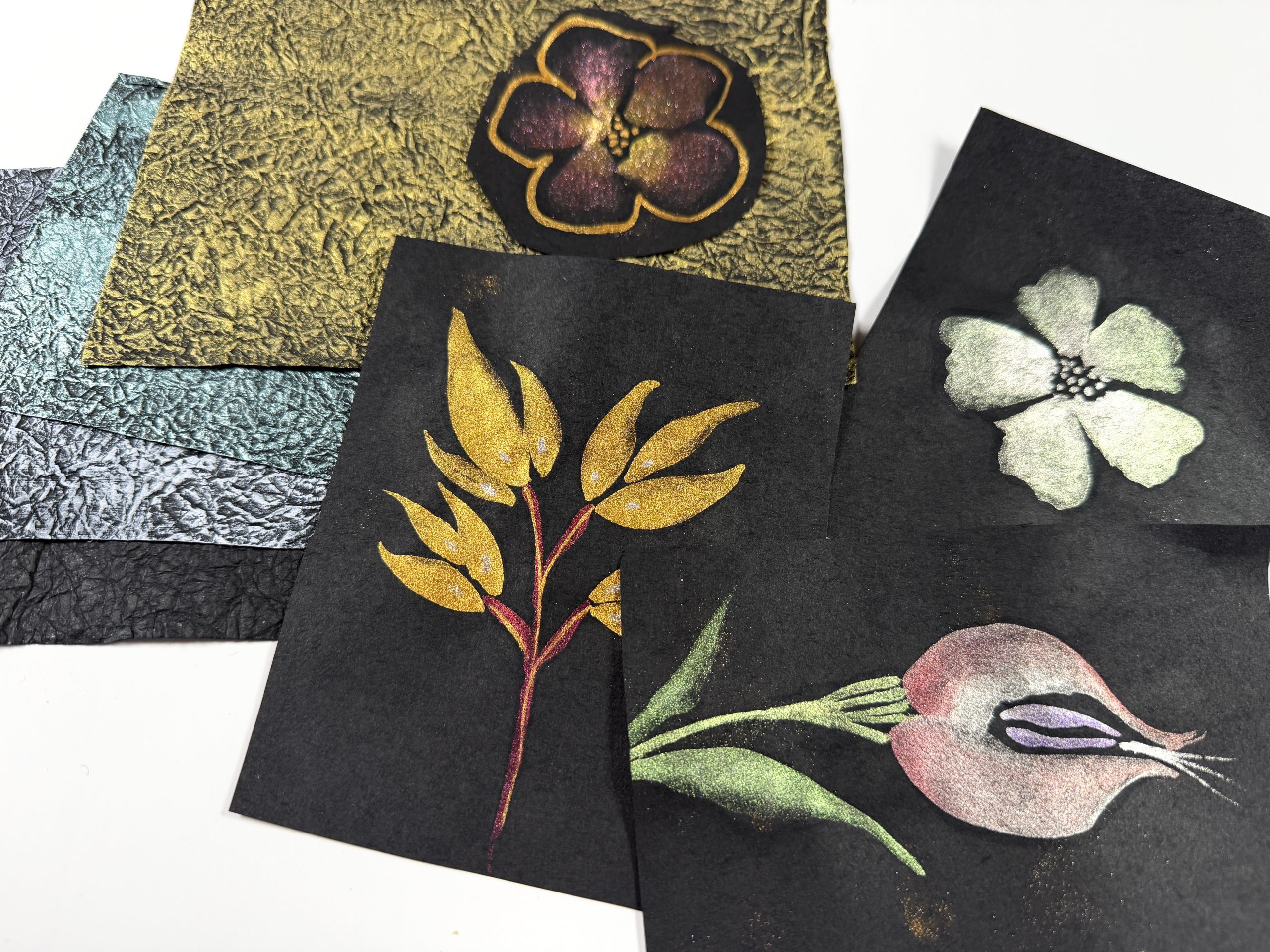 metallic florals painted on black washi paper with a stack of metallic brushed momigami sheets in the background