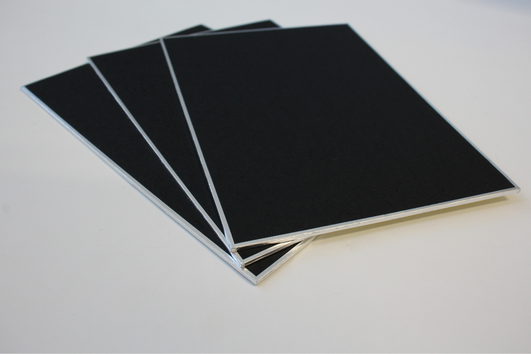 stack of three rectangular black shikishi boards with silver foil edges arranged in a fan